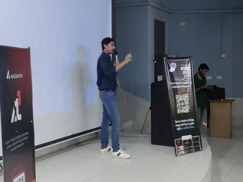 Muzammil on stage at an Avalanche event at Karachi University, mid-sentence, mic in hand.